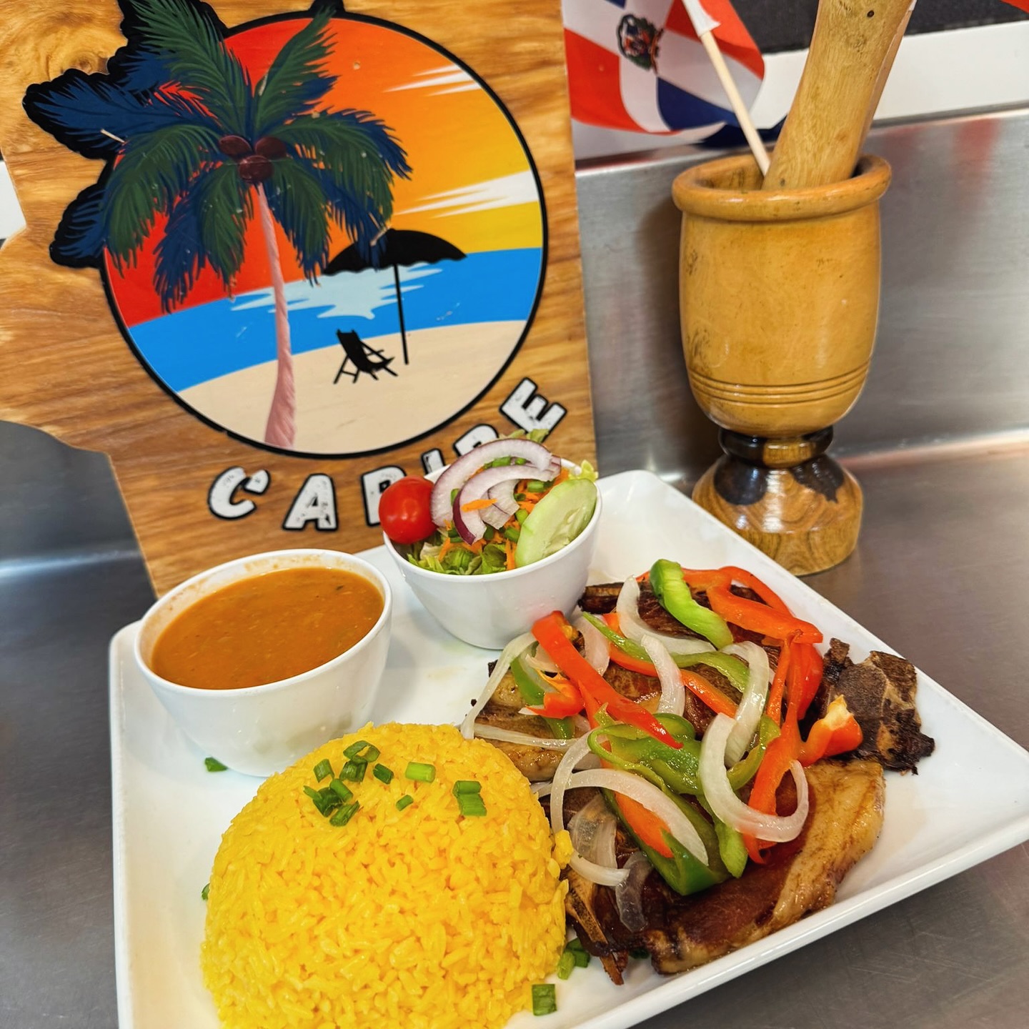 Grilled steak with peppers, yellow rice, and salad on a Caribe board