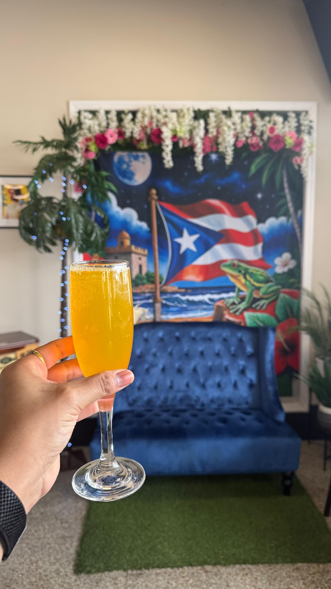 Bright orange mimosa held in front of the Caribe Puerto Rico mural with floral garland