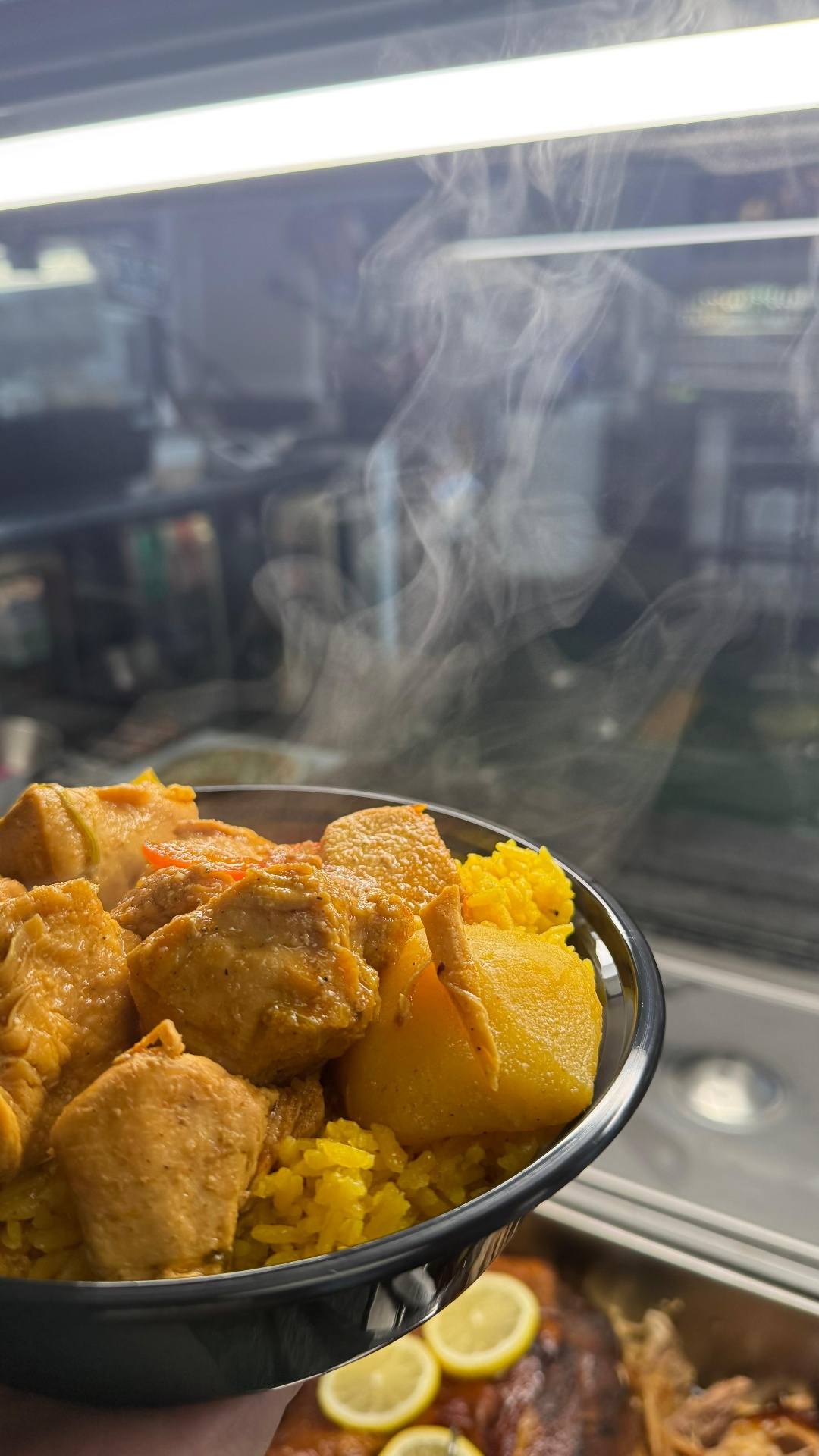 Steaming bowl of yellow curry chicken with potatoes over yellow rice